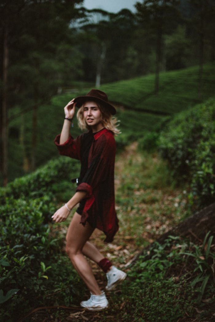 Young woman in hat running on trail in forest